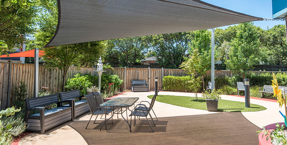 Outdoor table under shade with plants in the background