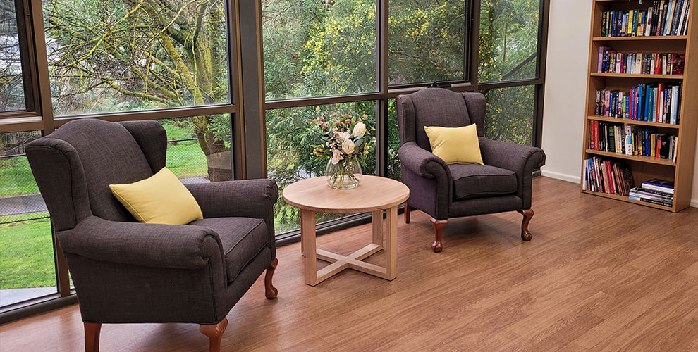 Sitting room with large windows filled with greenery