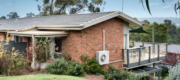 Exterior of red brick home with grey roof, front entrance can be seen to the left