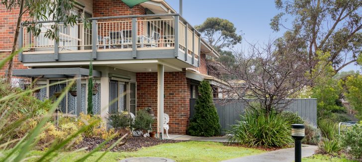 Brick home with a second floor balcony, a green shade provides shade over the balcony