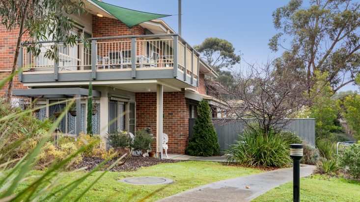 Brick home with a second floor balcony, a green shade provides shade over the balcony