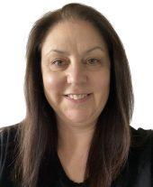 A woman with long brown hair wearing a black shirt smiles facing the camera