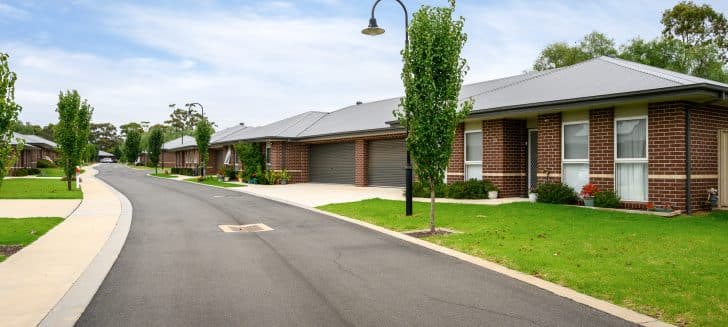 Brown brick houses with dark grey garages, lamppost in front yard