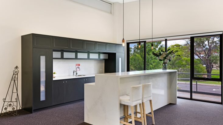 White bar stools sit under a kitchen island, pendants hang over it