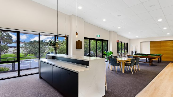 White kitchen island with black cabinets in foreground, dining chairs and pool tables behind