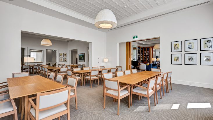 Expansive room with wooden dining sets, large white pendants hang down