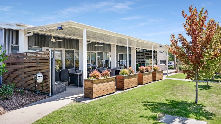 Outdoor seating underneath a covered patio, wooden planter boxes in foreground