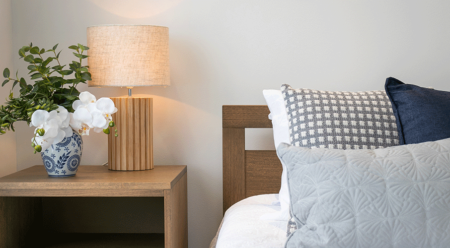 Close up of bed and bedside table with lamp on