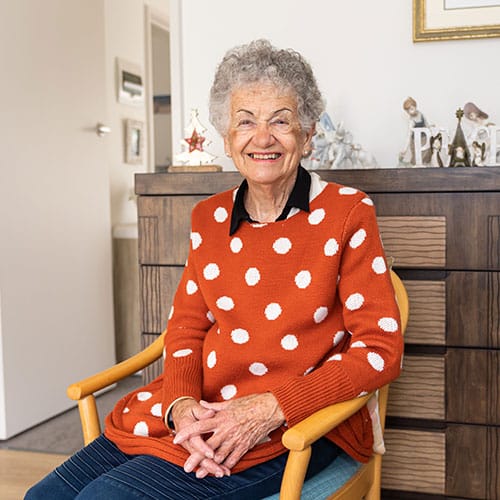 Woman sitting on a chair in her home, smiling