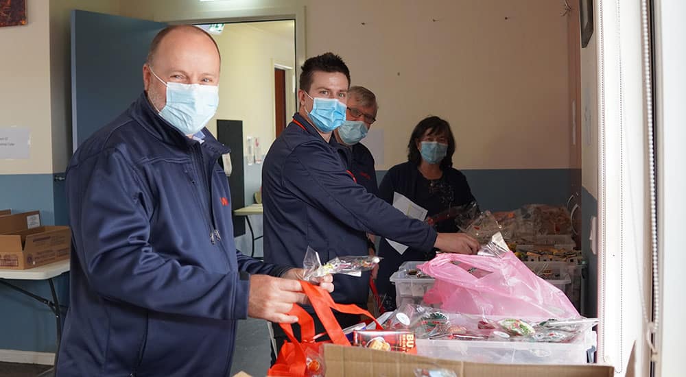 Four staff members, packing gifts into Christmas Hampers