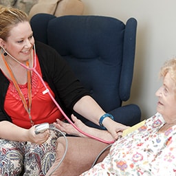 Nurse checking older woman's vitals