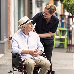 Woman wheeling elderly man in his wheel chair