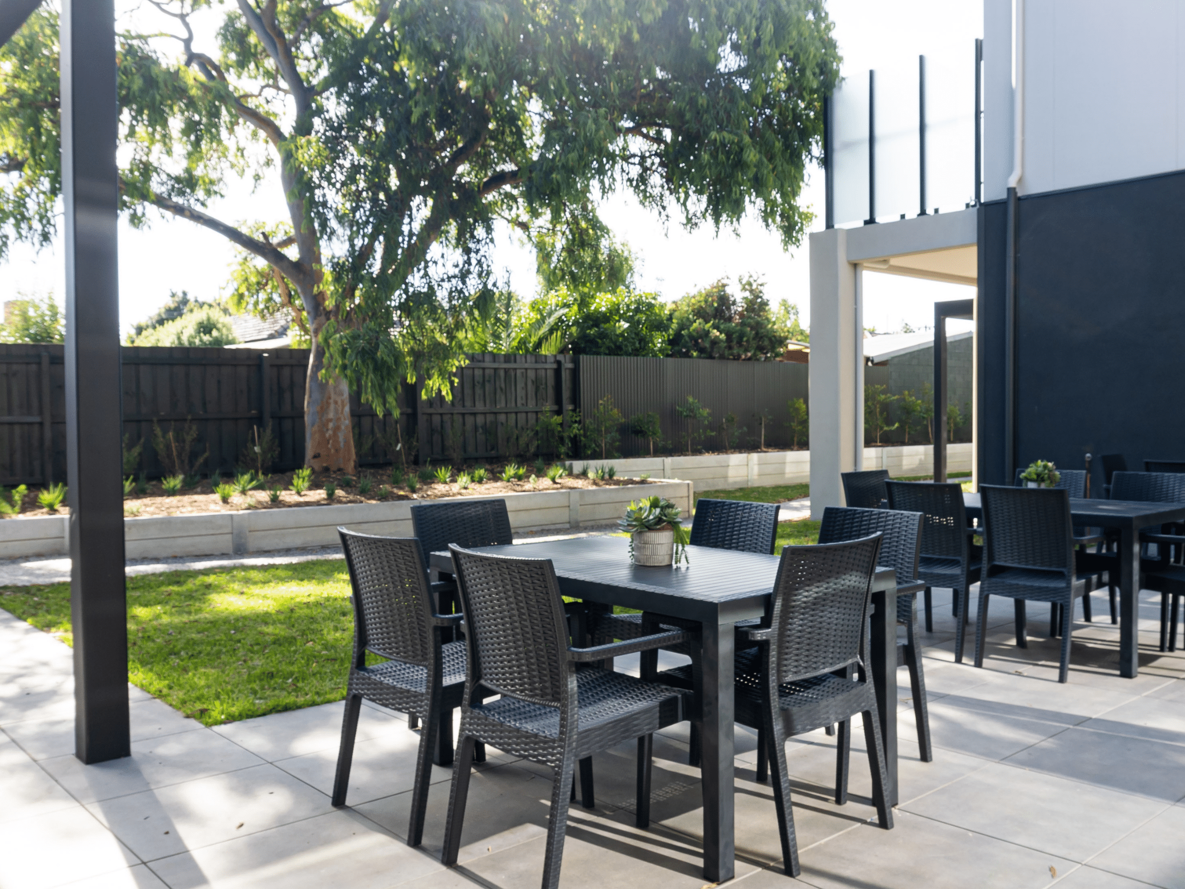 A courtyard with tree, grass and tables and chairs