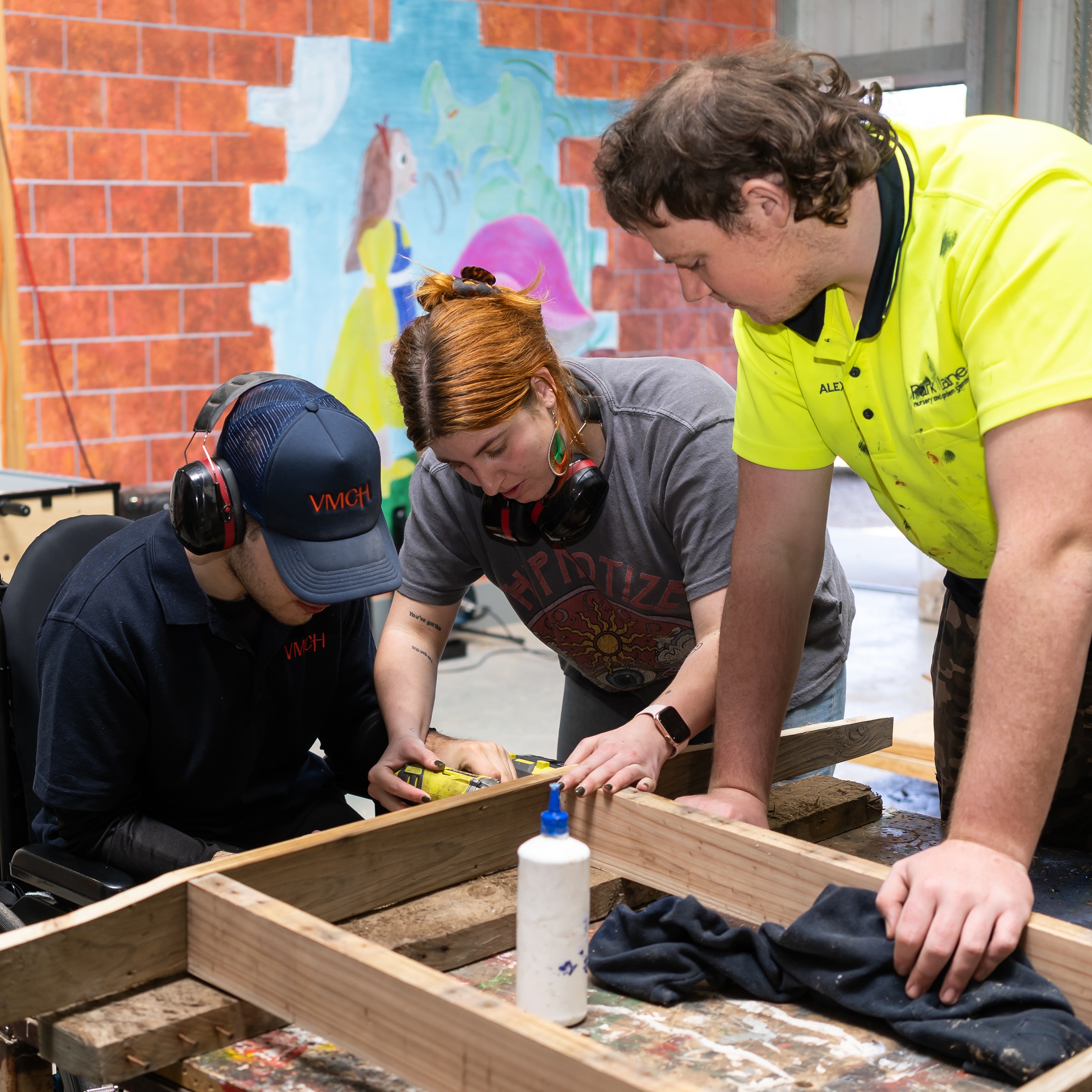 Three people working together on a woodworking project