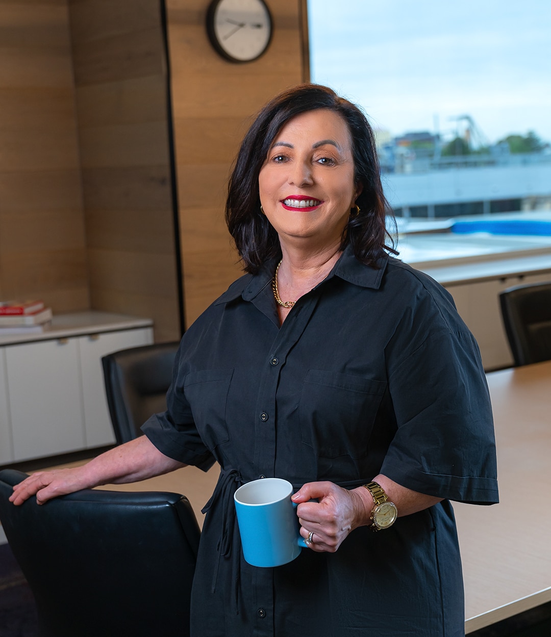 Woman smiling, holding blue mug