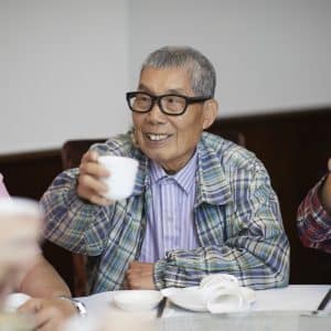 Man smiling and raising his tea in celebration