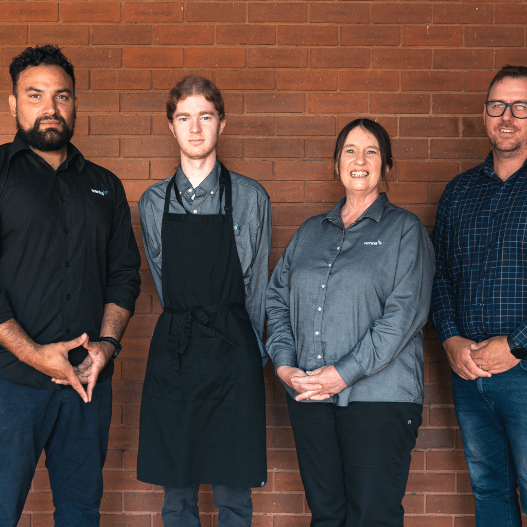 Three men and a woman stand in front of a brick wall