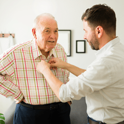 Nurse helping older man get dressed