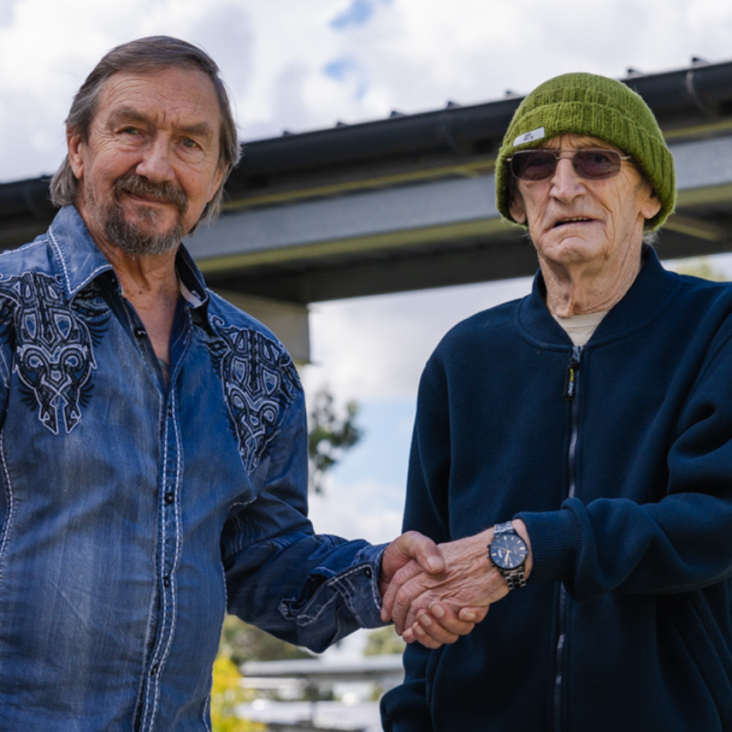 Two men stand and shake hands