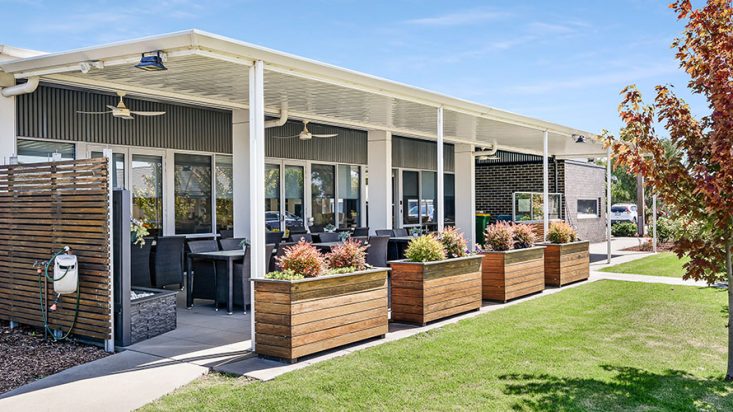 Patio with dining chairs at Shanagolden Community Centre, garden boxes in the foreground and tree visible to the right