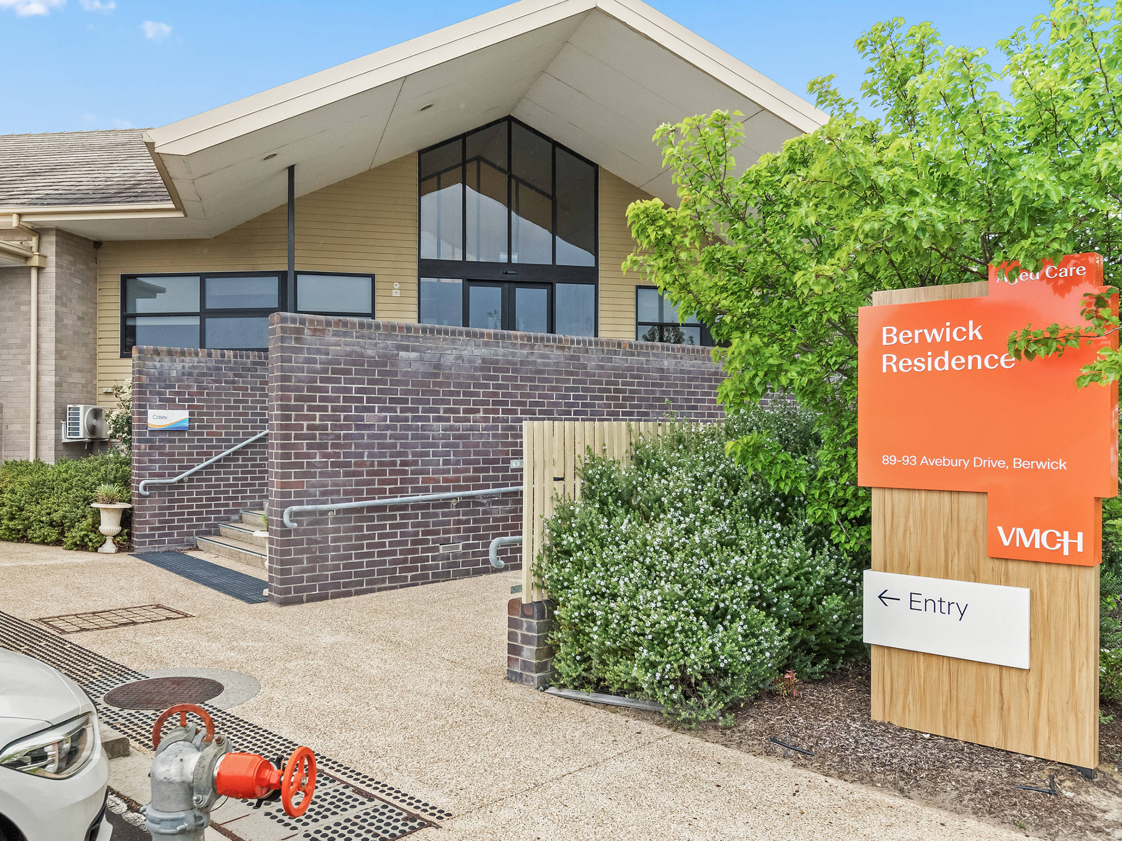 The outside of a large building. There are trees surrounding the building and a sign that reads 'VMCH Berwick Aged Care Residence'