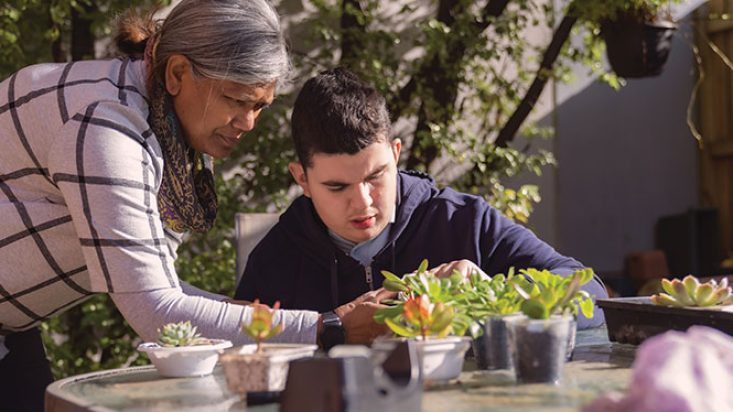 A boy and his carer tending to plants