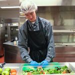 A man in a kitchen, chopping