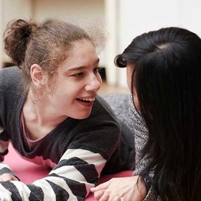 Girl with grey and white stripe jumper on laughing at carer