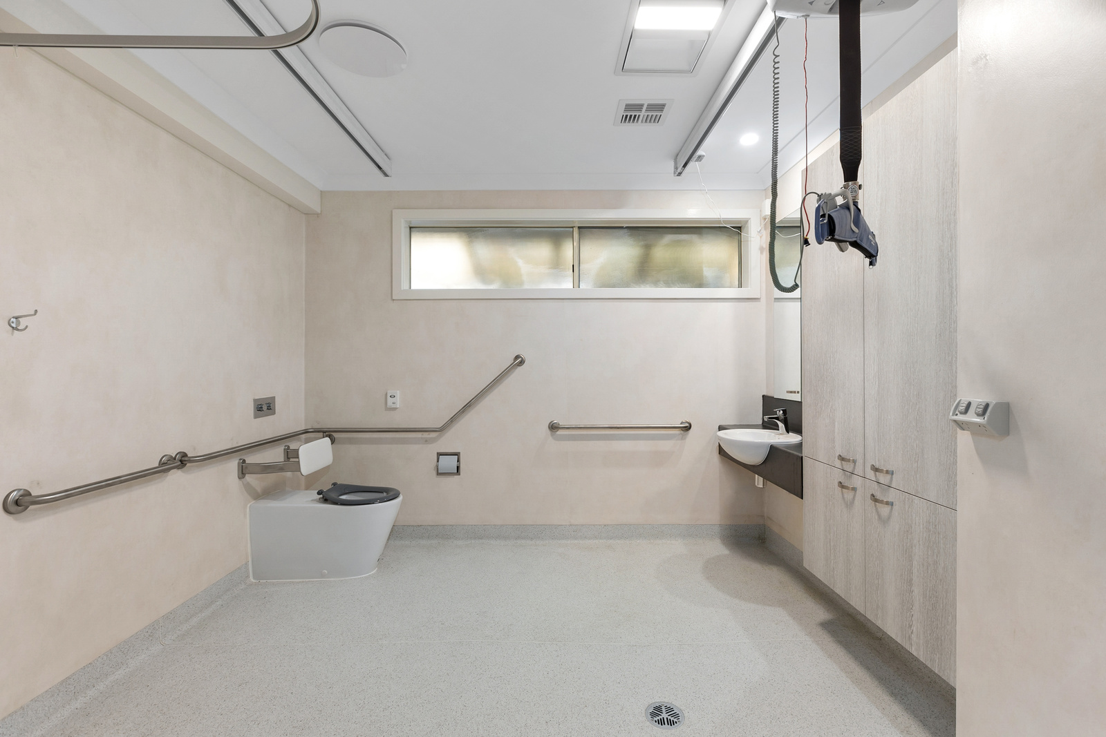 A large bathroom with rails for accessibility.