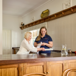 A younger woman helps an older woman in the kitchen