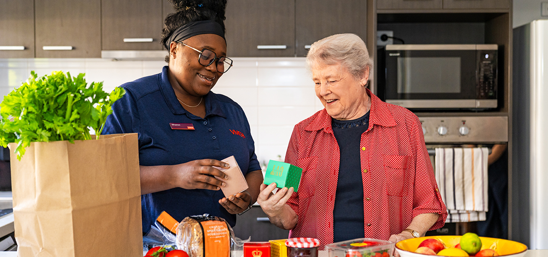 Two women look at food items in a kitchen