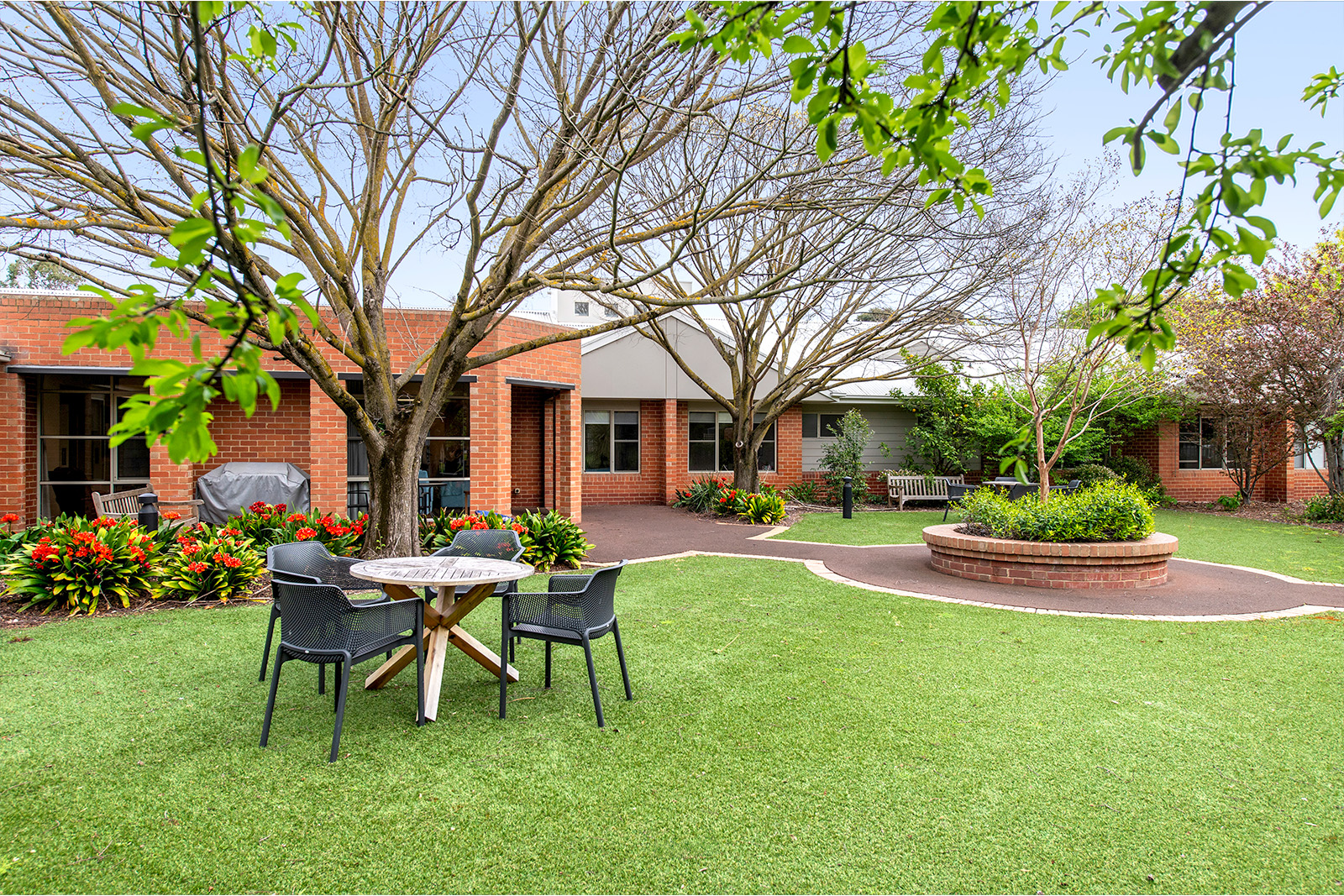 A table and chairs set on the grass near a redbrick building.