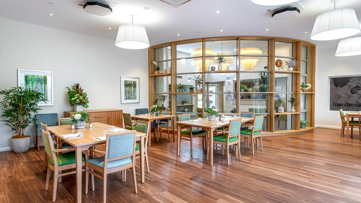 A dining room with large windows that overlooks a living space.