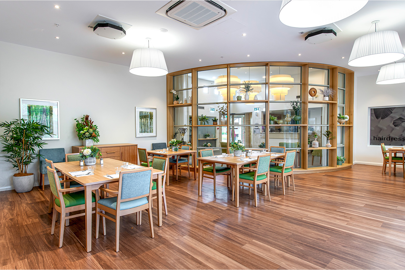 A dining room with large windows that overlooks a living space.