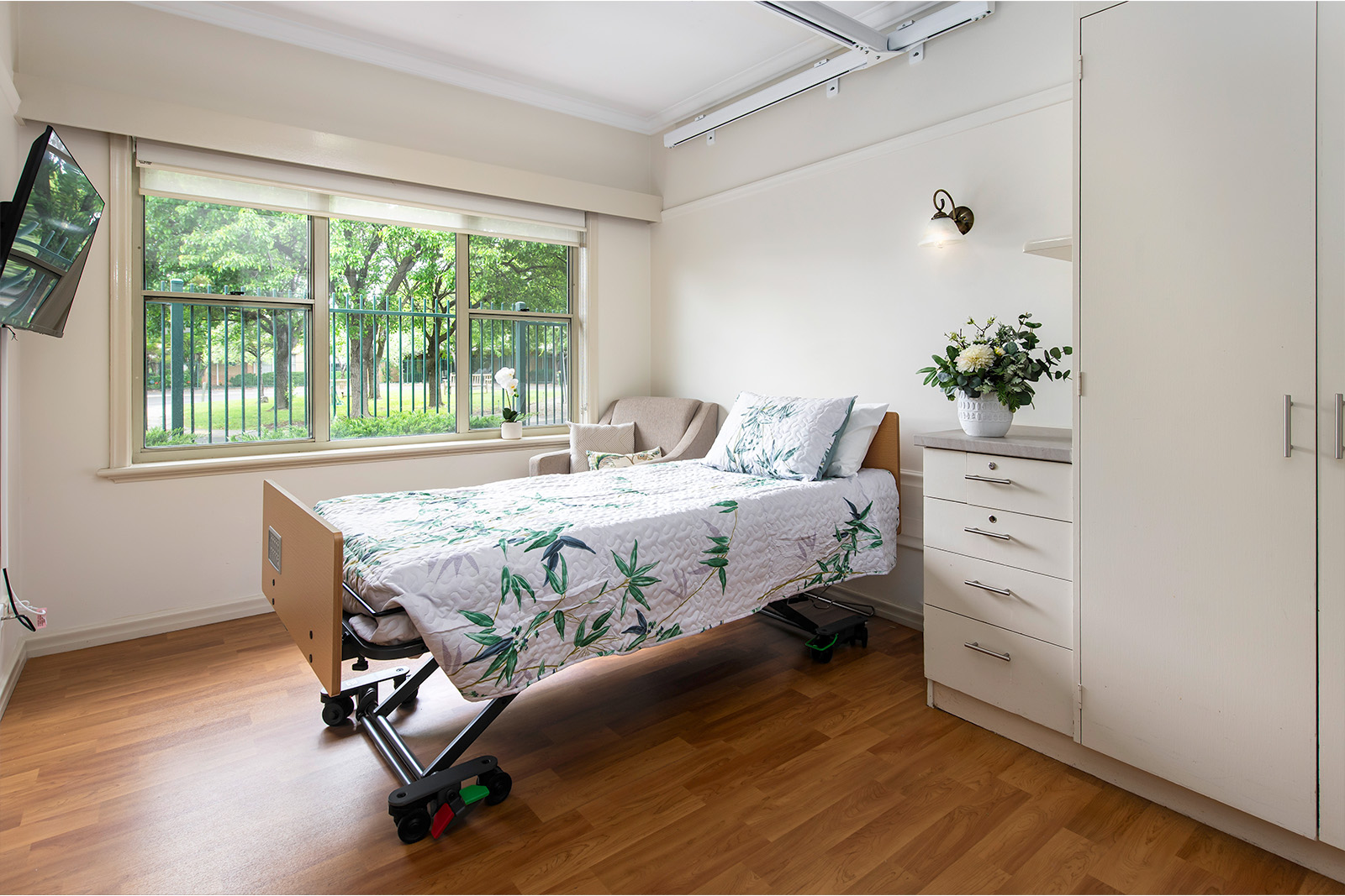 A bedroom with a large window and an armchair in the corner beside the bed.