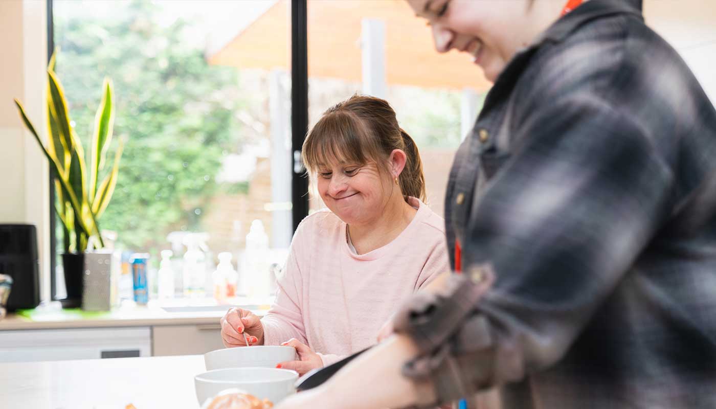 A woman and her support worker are cooking in the kitchen