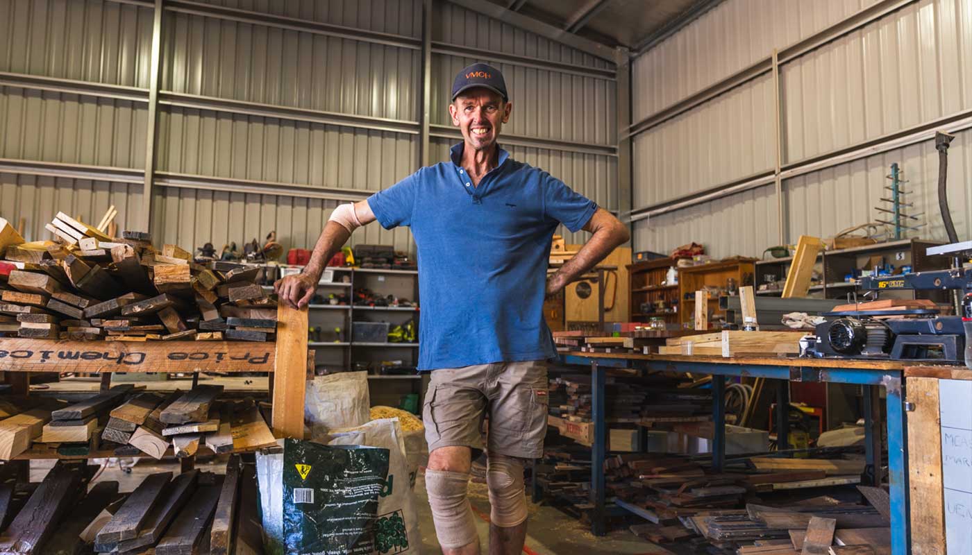 A man in blue t-shirt, standing in a woodworking warehouse