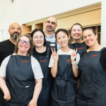 A group of people wearing aprons smile at the camera.