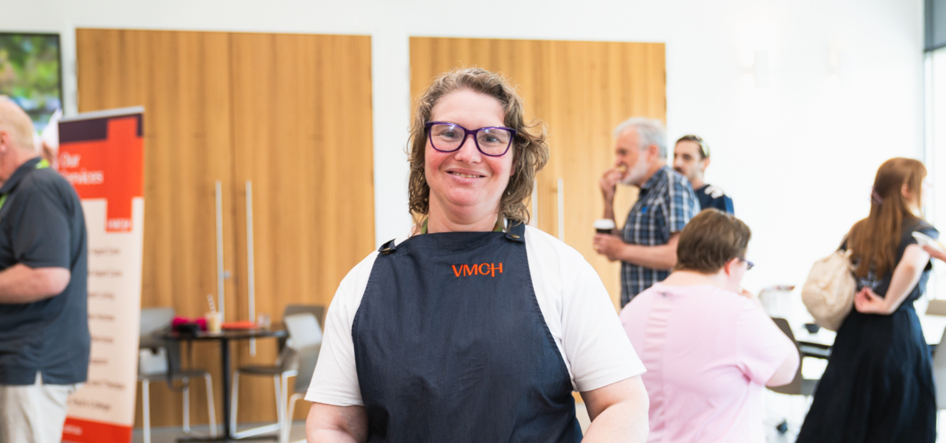 A woman wearing an apron smiles at the camera