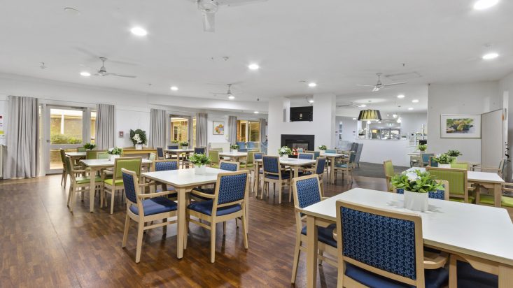 A bright dining room with many tables at St Bernadette's Aged Care.