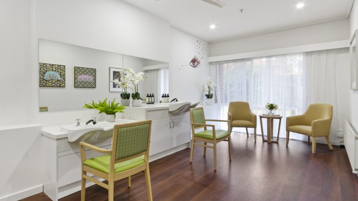 A bright salon with green chairs and two basins at St Bernadette's Aged Care.