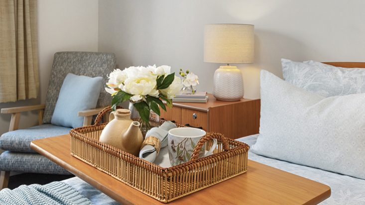 A tray with a tea set laid across a table that is across a bed.