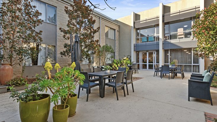 A courtyard with pot plants and tables arranged.