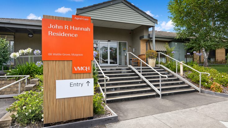 Stairs leading into a small building with a bright vermillion sign saying John R Hannah Residence.