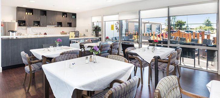 A dining room with comfortable chairs at multiple tables at Shangolden Aged Care Pakenham.