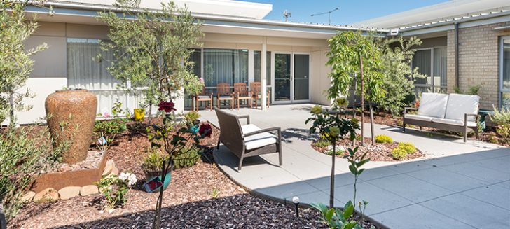 A courtyard with outdoor furniture on a paved path at Shangolden Aged Care Pakenham.