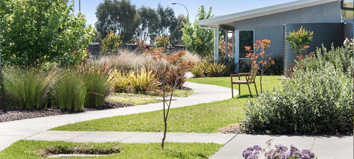 A garden with a paved path winding along the bushes at Shangolden Aged Care Pakenham.