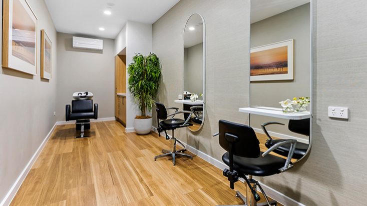 A salon with big, rounded mirrors and a large potted plant in the corner.