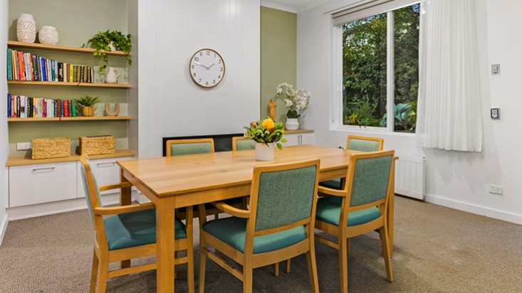 A cosy room with a dinner table and books on shelves behind it.