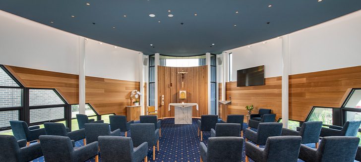 A chapel with blue armchairs arranged to face the altar.